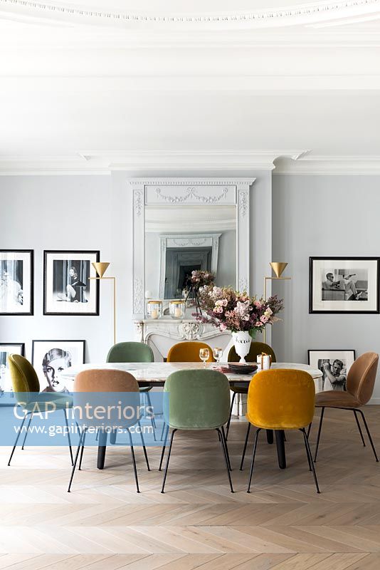 Different coloured chairs around vintage dining table 