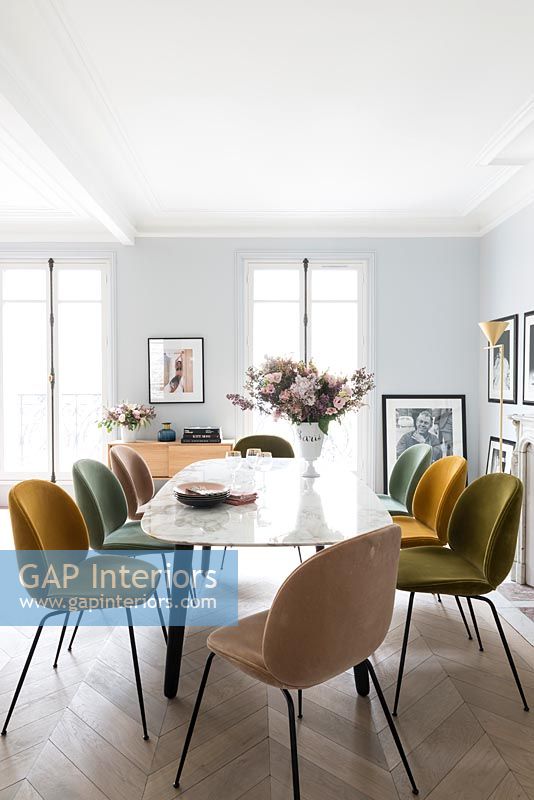 Different coloured upholstered chairs around vintage marble dining table 