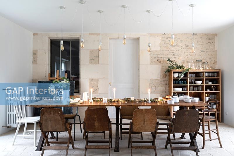 Country dining room with exposed stone feature wall and wooden table 