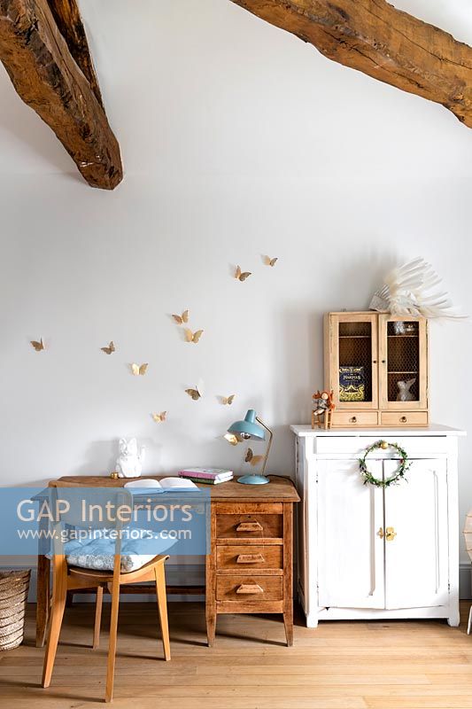 Desk and chair in childrens room with exposed wooden beams 
