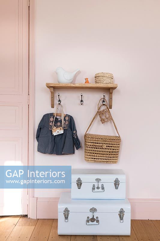Suitcases and accessories under wall mounted coat hooks in childs room 