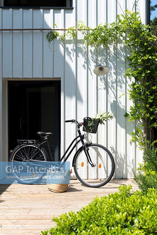 Bicycle and shopping basket by front door of modern country house 