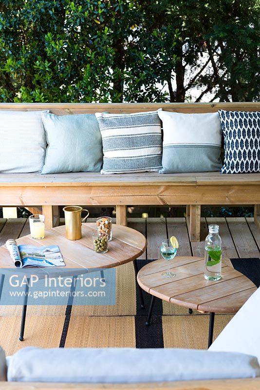 Wooden furniture and variety of cushions in blue tones - outdoor living room