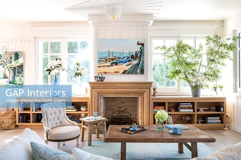Nautical painting above wooden fireplace in country living room 