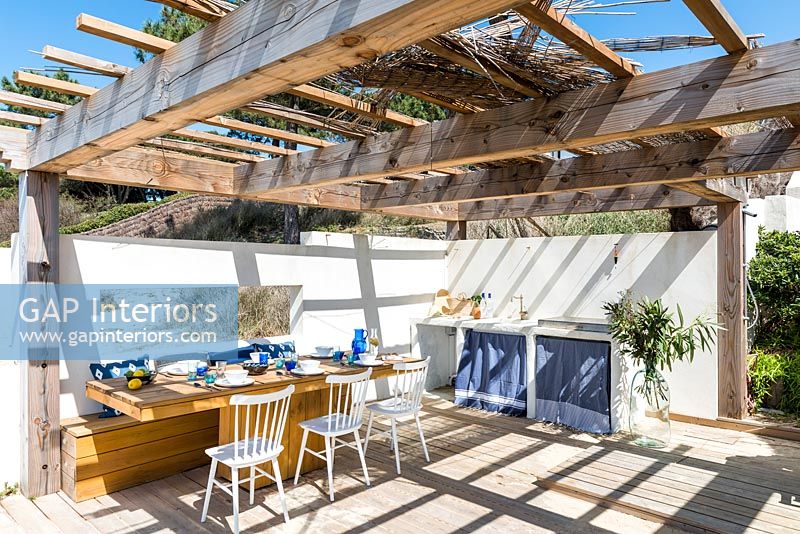 Outdoor kitchen and dining area under pergola 