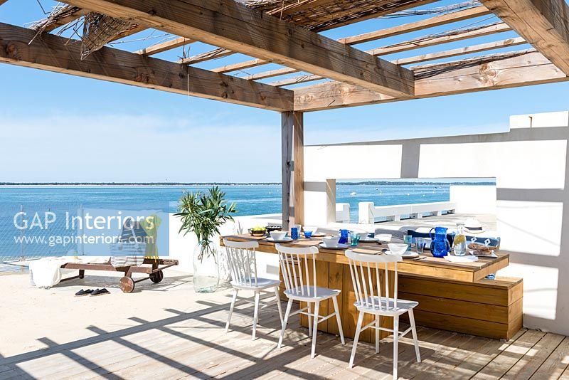 Outdoor dining area on decking overlooking sea 