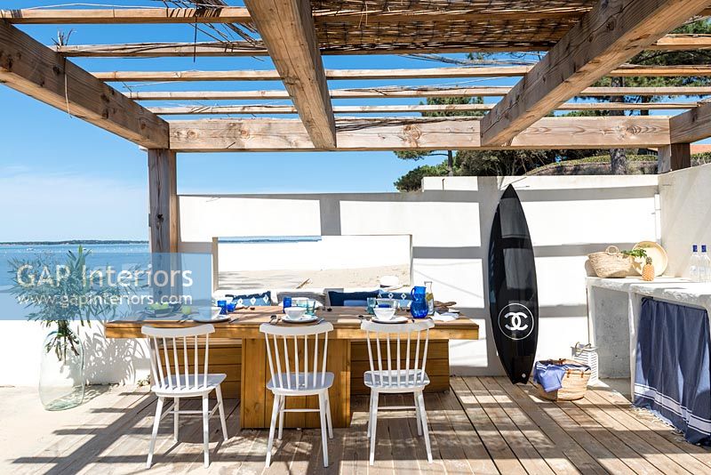 Surfboard in outdoor kitchen-diner overlooking sea 