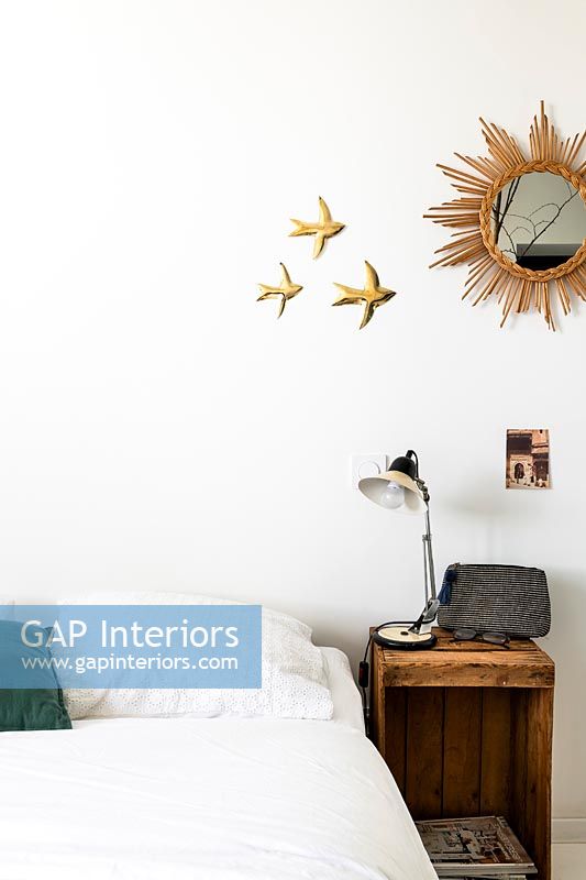 Sunburst mirror and gold swifts on wall of white bedroom 