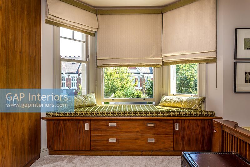 Built-in window seat with storage and gold cushions 