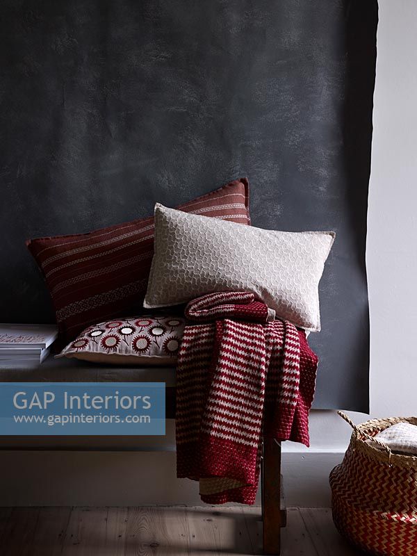 Red and white soft furnishings against black fabric wall hanging  