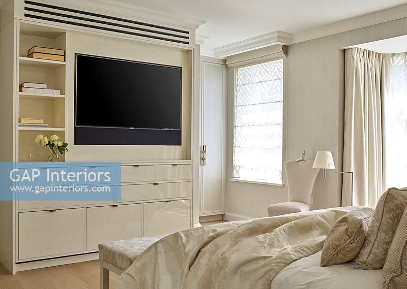 Modern cream bedroom with built-in television in wall cabinet