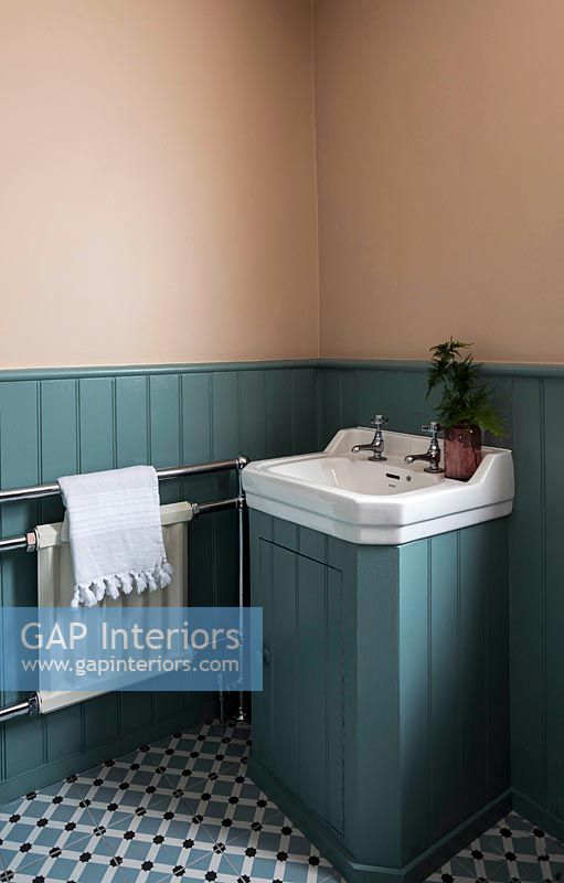 White sink unit in blue painted wood paneled bathroom 