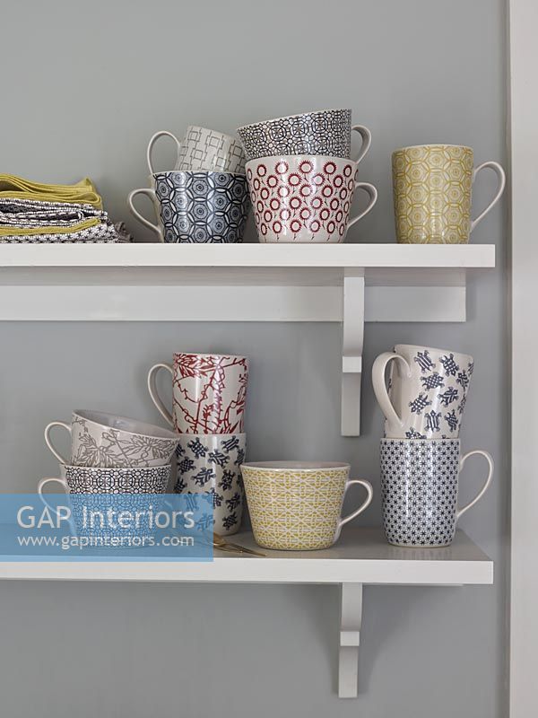 Variety of patterned mugs on shelves 