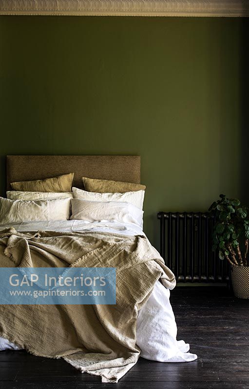 Cream bedding in dark green painted bedroom 