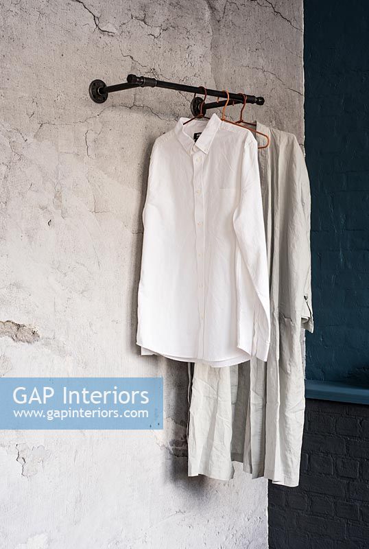 Linen shirts hanging on wall mounted clothes rail 