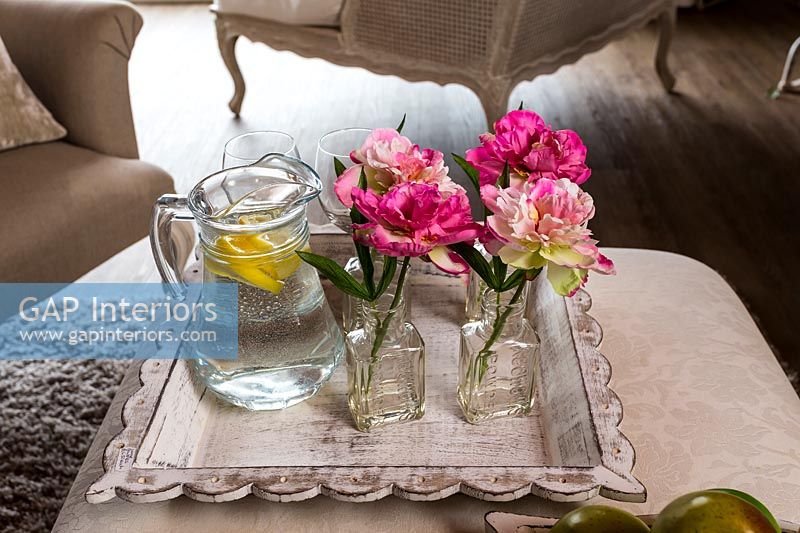 Flowers in vases with jug of water on tray 
