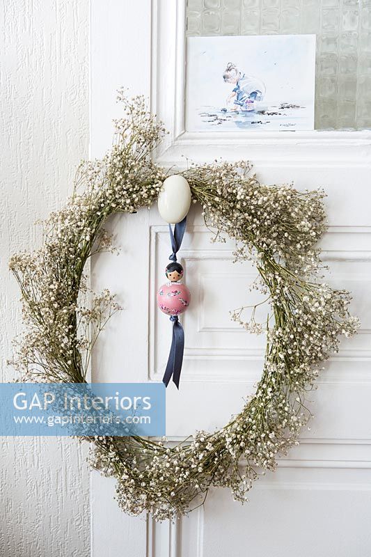 Floral wreath and toy on ribbon hanging on door handle 