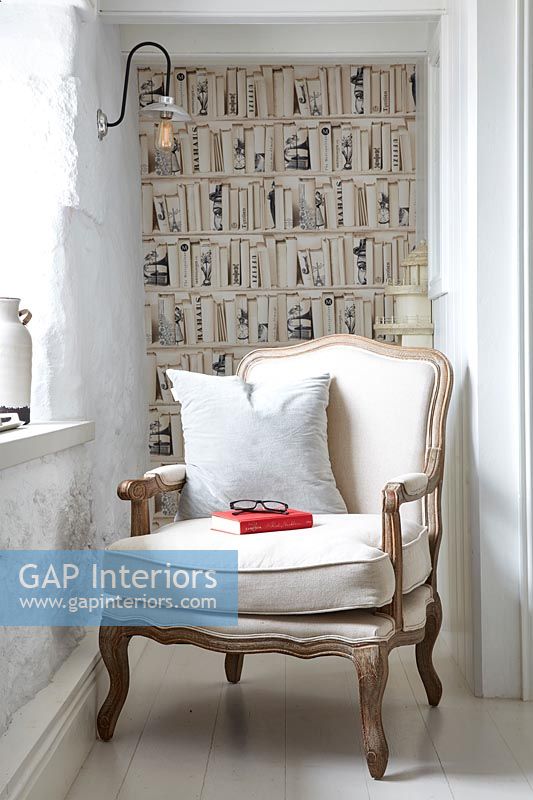 Bookshelf wallpaper in alcove with armchair