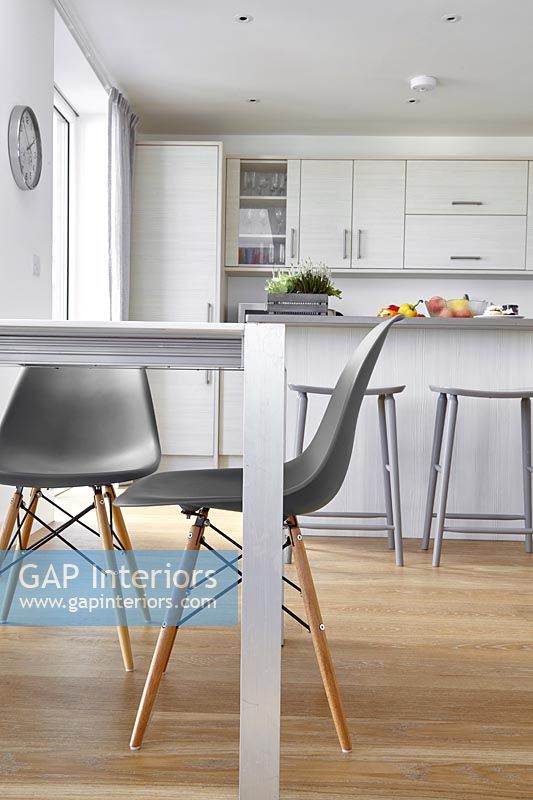 Grey chairs in modern white kitchen-diner with wooden floor 