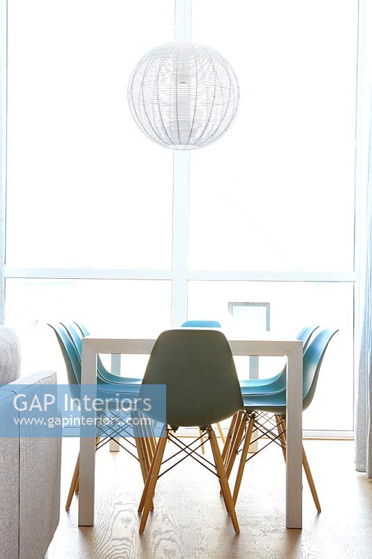 Turquoise chairs around dining table in modern white dining room 