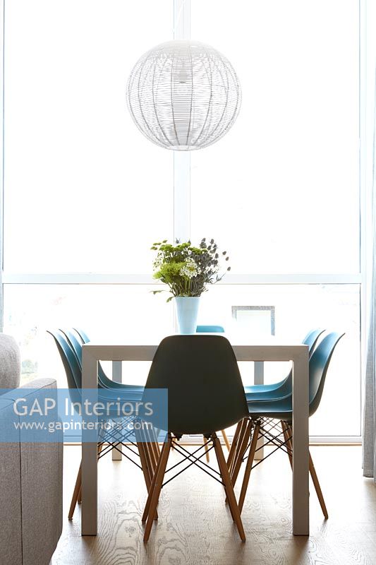 Modern dining room with full length windows and turquoise chairs 