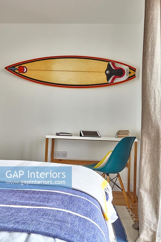 Surfboard on wall of bedroom over desk 