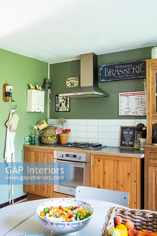 Country kitchen diner with wooden cabinets and green painted wall 