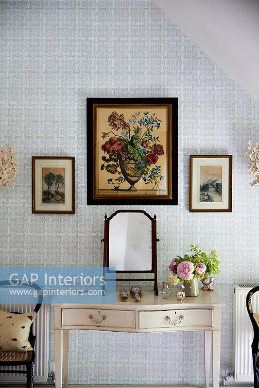 Floral painting above dressing table in country bedroom 