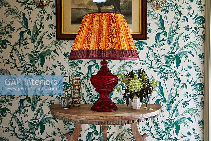 Large orange lamp on wooden console table in hallway 