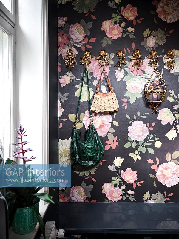 Floral wallpapered wall with decorative gold hooks