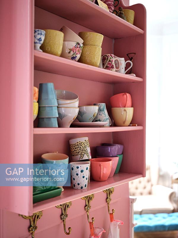 Pink painted shelves against pink painted wall in modern kitchen 