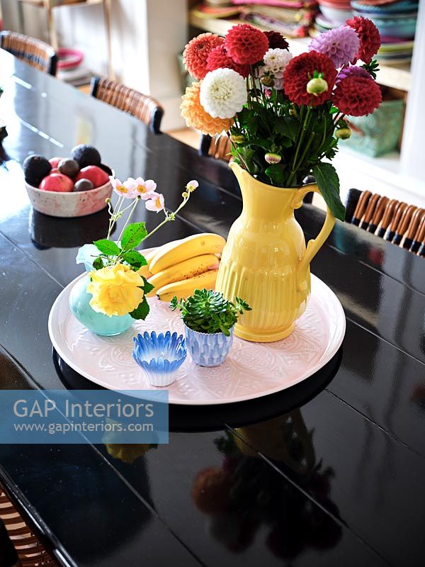 Yellow vase on pink tray on modern black dining table 