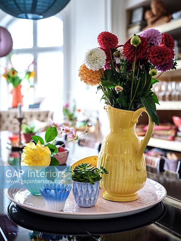Yellow vase of dahlias on pink tray 