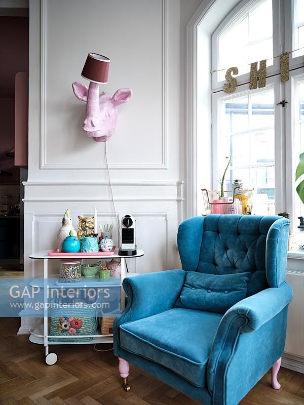 Pink rhino lamp over drinks trolley and blue armchair with pink legs 