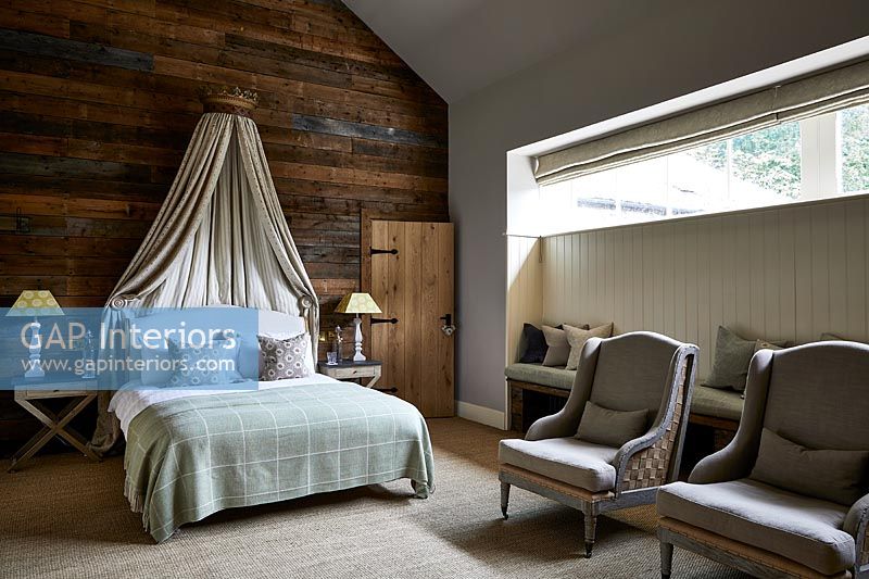Country bedroom with wooden feature wall and canopy over bed 