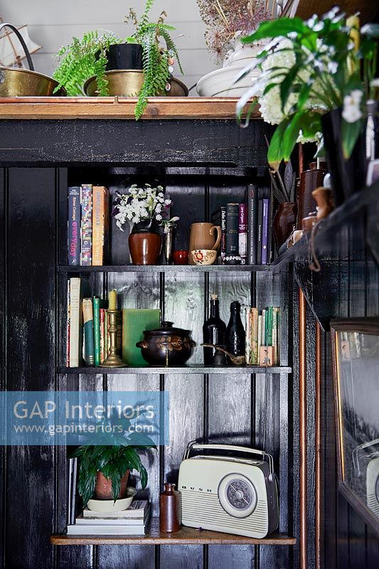 Black painted wooden unit with radio, books and ornaments 
