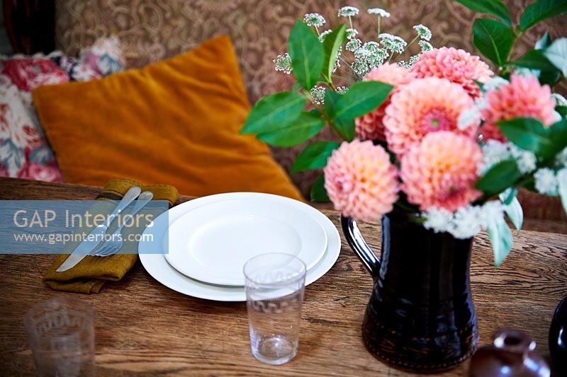 Flower arrangement in black jug on country dining table 