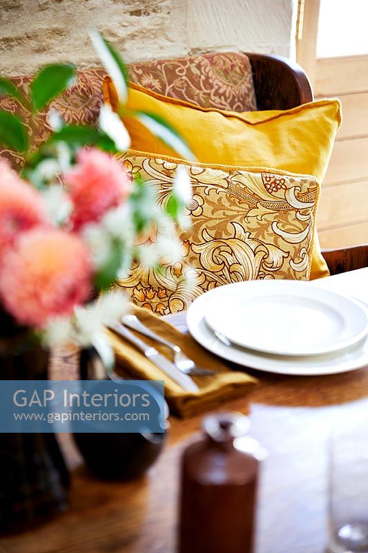 Floral cushions on seat next to country dining table 