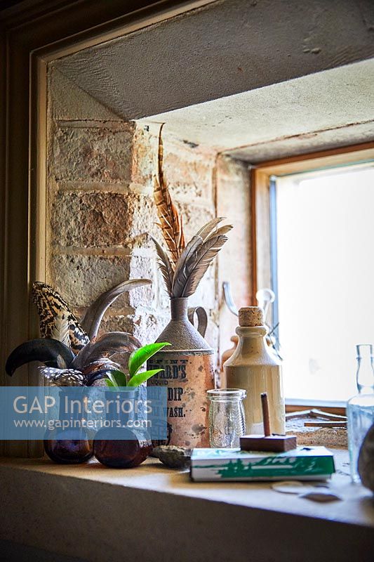 Bird feathers in vases and pots on windowsill 