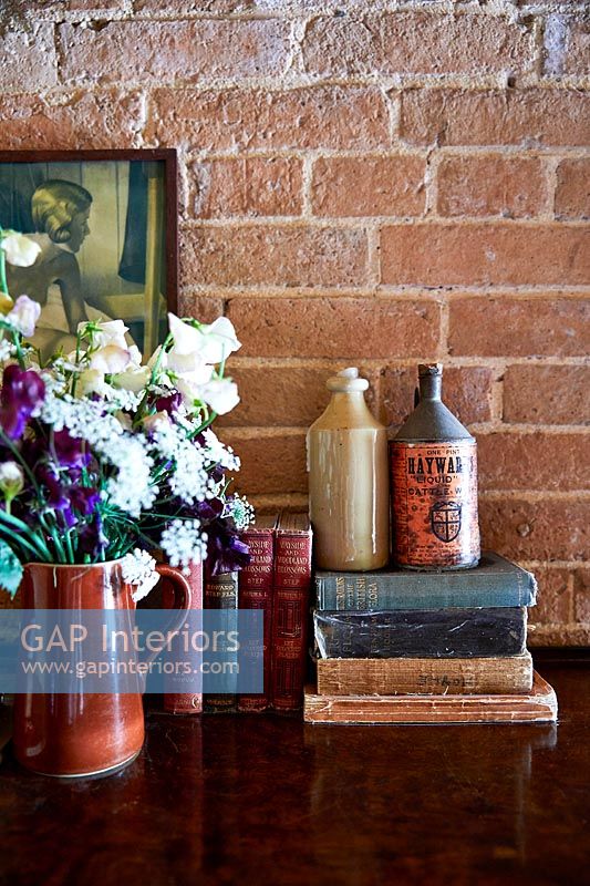 Books, vintage ceramic bottles and flowers in vase 