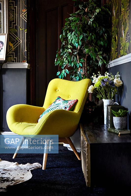 Yellow chair in dark painted eclectic living room 