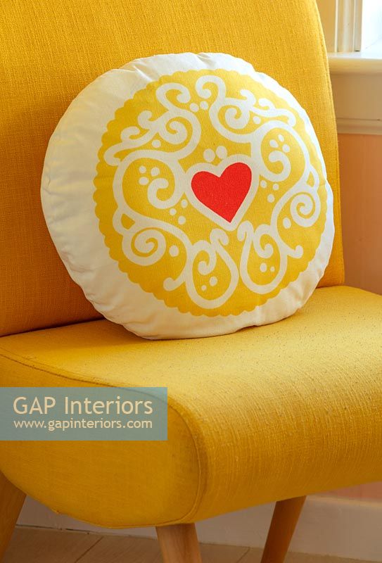 Yellow cushion with red heart motif on yellow chair