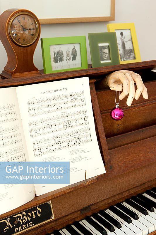 Upright piano with model hand holding bauble 