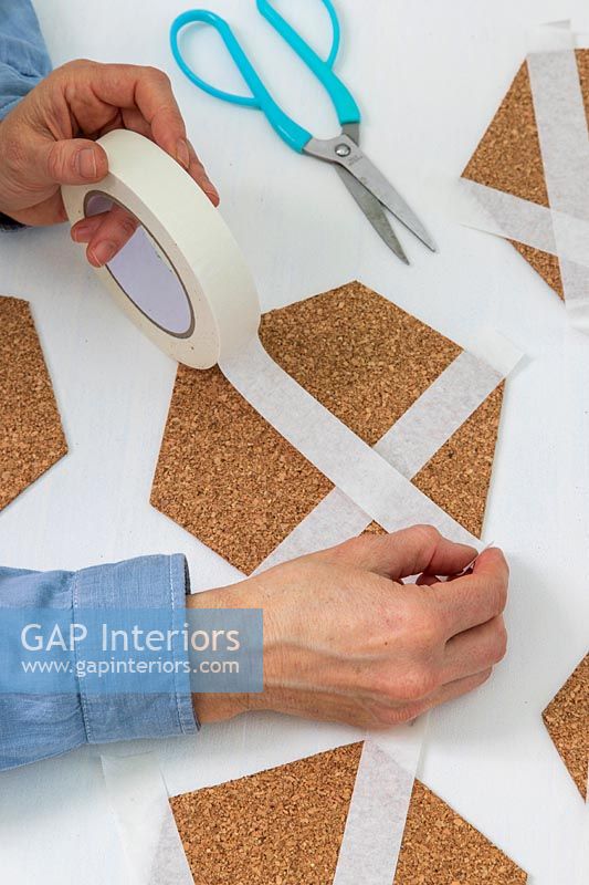 Woman adding masking tape to cut out hexagonal shapes
