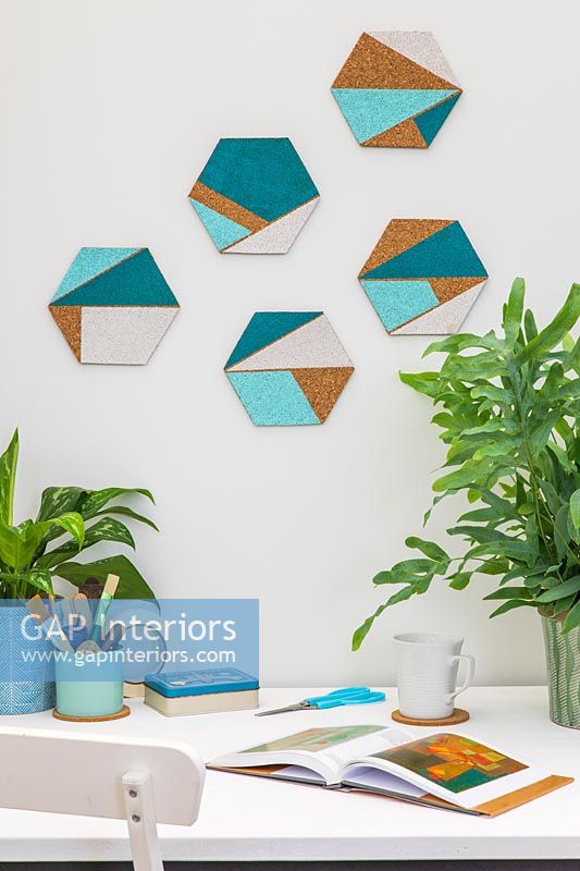Hexagonal cork shapes with painted geometric areas used for wall decorations above desk