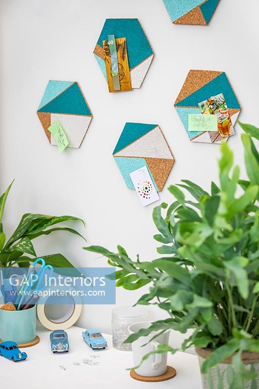 Hexagonal cork shapes with painted geometric areas used for decorative pinboards above desk