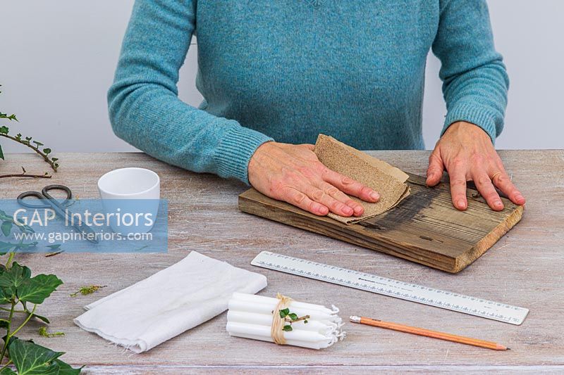 Woman sanding piece of wood with fine sandpaper