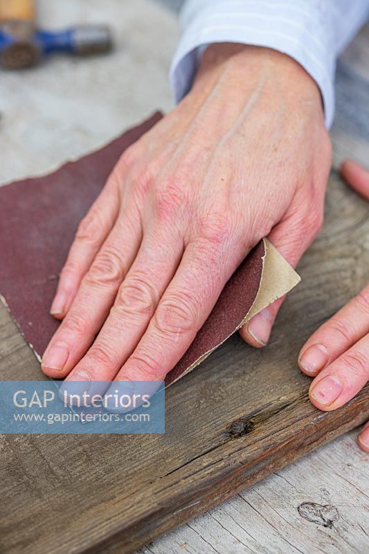 Close up detail of woman sanding down piece of wood with fine sandpaper