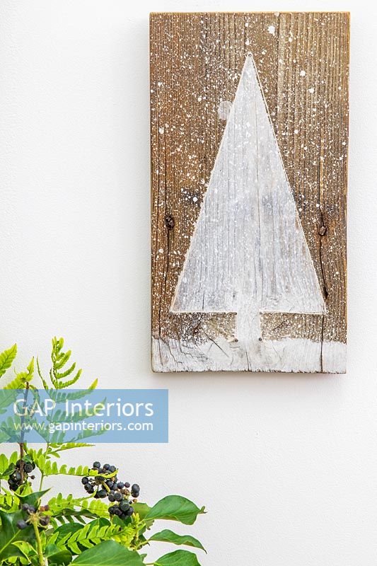 Christmas tree themed wall hanging made of wood decorated with paint and string fixed to wall
