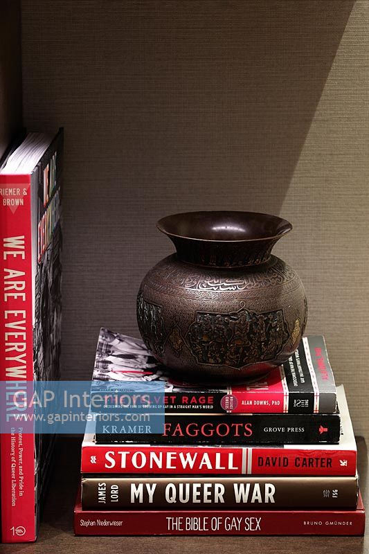 Books and metal vase on bookshelf 